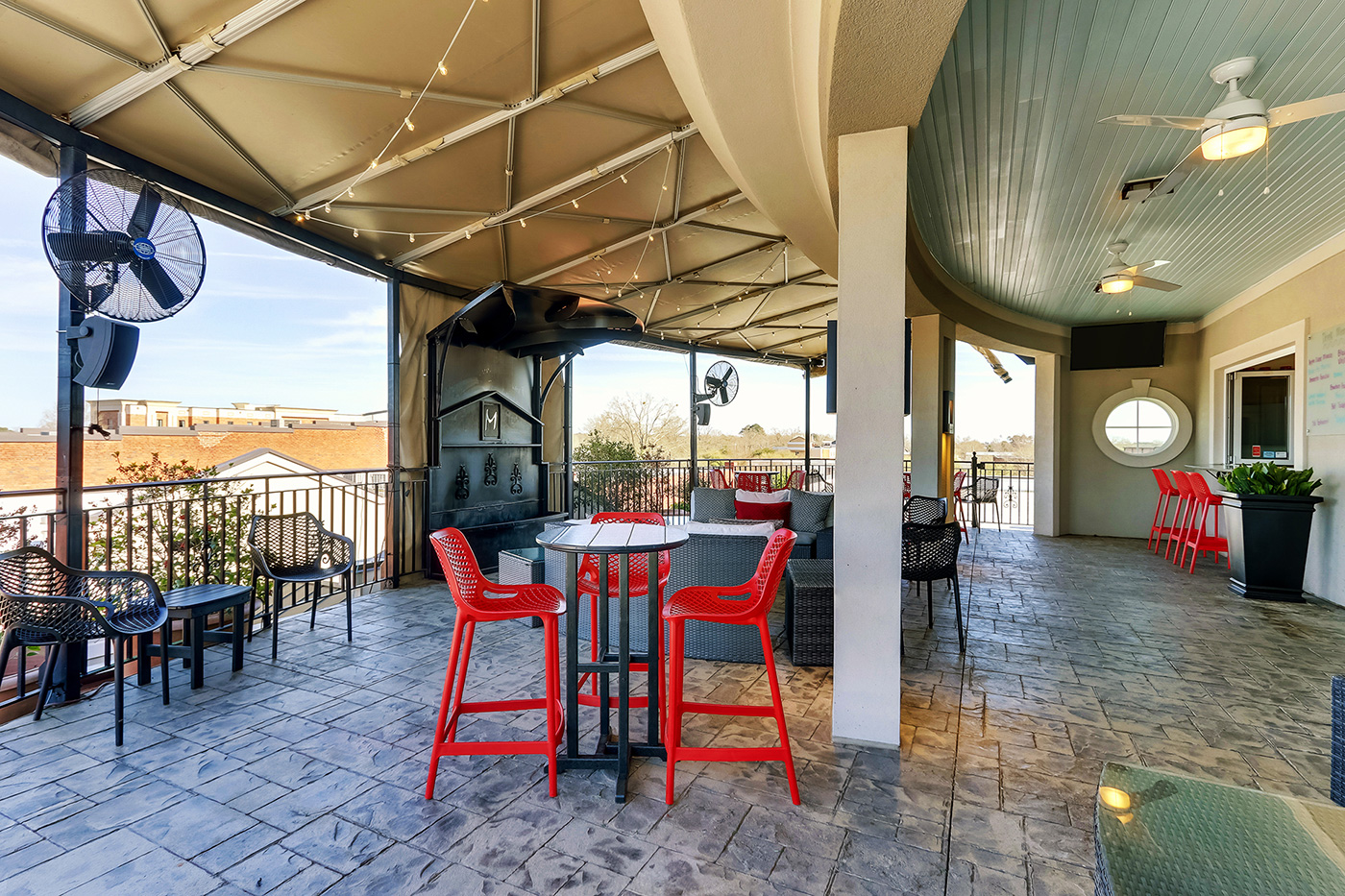 Guests gathered at the rooftop rail at dusk as the bartender pours drinks at the service window