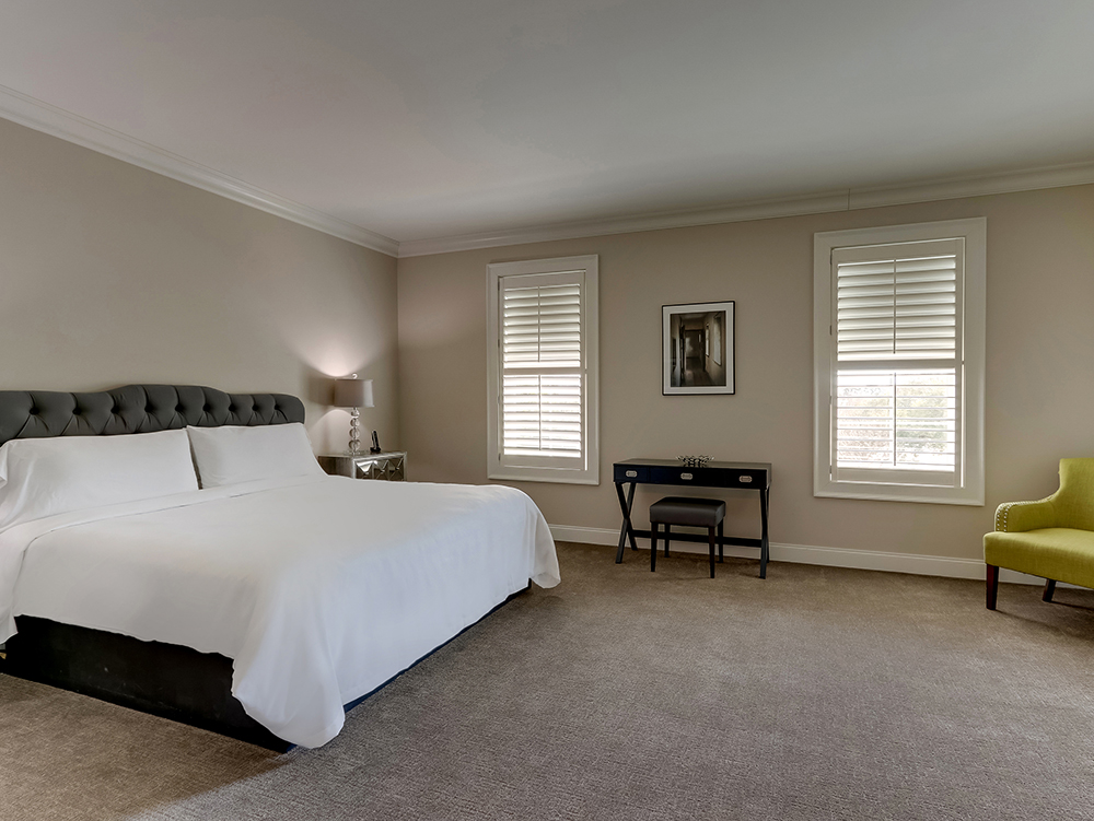 A Deluxe King suite at The Mantissa with a premium bed, warm lamplight and a residential feel