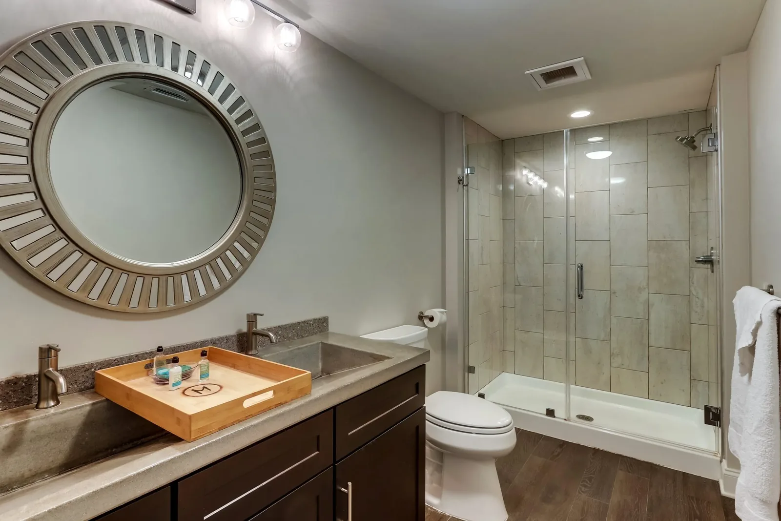 The marble bath of the Balcony King, a double vanity under a round sunburst mirror beside the glass walk-in shower.