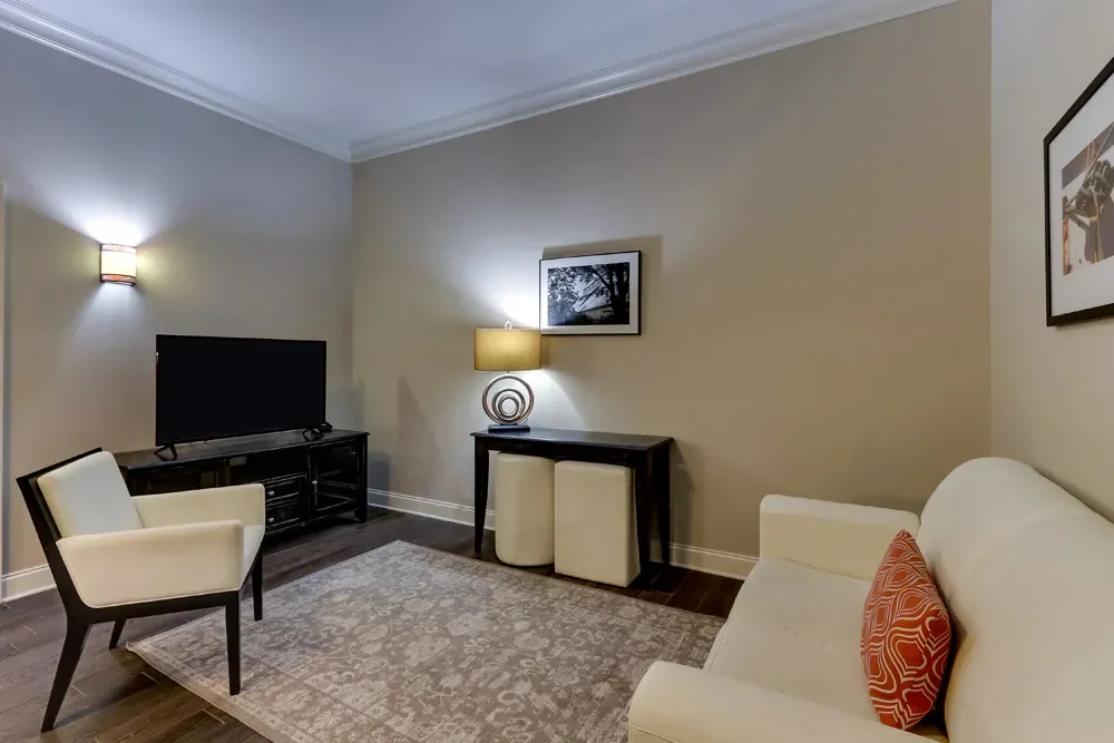 The sitting room of the Classic Dual Queen, a cream sofa and armchair around the television.