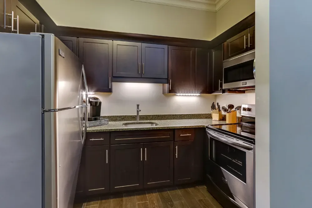 The Classic Dual Queen's full kitchen, dark cabinets with stainless appliances under cabinet lighting.