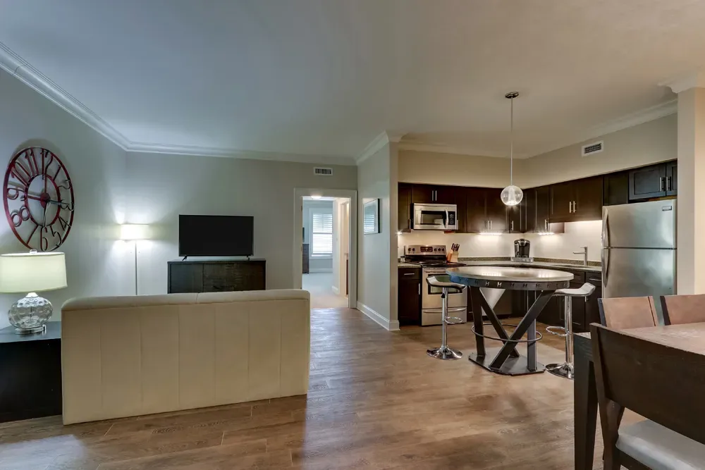 The living area of the Deluxe Dual Queen, a sofa and high-top table opening into the full kitchen.